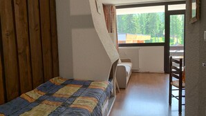 Un dormitorio con cama, una silla, un ventanal y vistas al exterior.