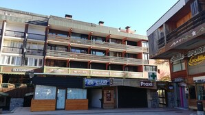 Un edificio de varios pisos con diversos comercios en la planta baja, incluyendo una pizzería y una tienda de deportes.