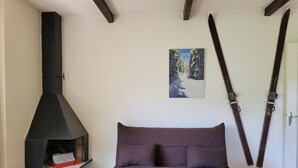 Une pièce avec un canapé, une cheminée et des paires de skis accrochées au mur.