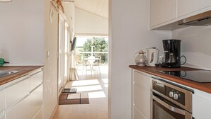 Uma cozinha moderna com bancada de madeira, eletrodomésticos de aço inoxidável e vista para um pátio externo.