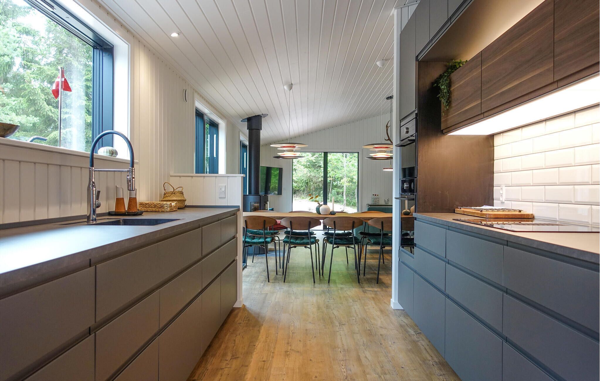 Une cuisine moderne dotée d’un îlot central, d’appareils électroménagers intégrés et offrant une vue sur l’extérieur.