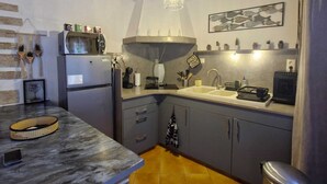 Een keuken met een marmeren aanrechtblad, een inbouwoven, een spoelbak en een hanglamp.
