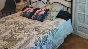 Een slaapkamer met een bed, een stoel, een bureau, een hanglamp en een decoratief wandobject.