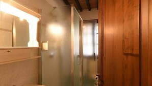 Une salle de bain avec une douche à parois de verre, une porte en bois et un miroir avec un éclairage au-dessus du lavabo.
