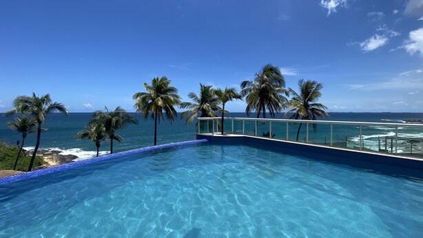 Une piscine d’un bleu éclatant, avec vue sur l’océan et les palmiers.