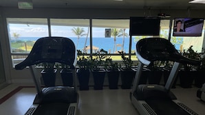 Une salle de sport équipée de tapis de course, agrémentée de plantes en pot et offrant une vue sur l’océan.