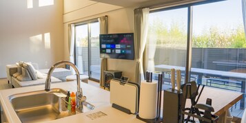 Una cocina moderna con un lavamanos, un televisor de pantalla plana y un comedor con mesa y sillas.