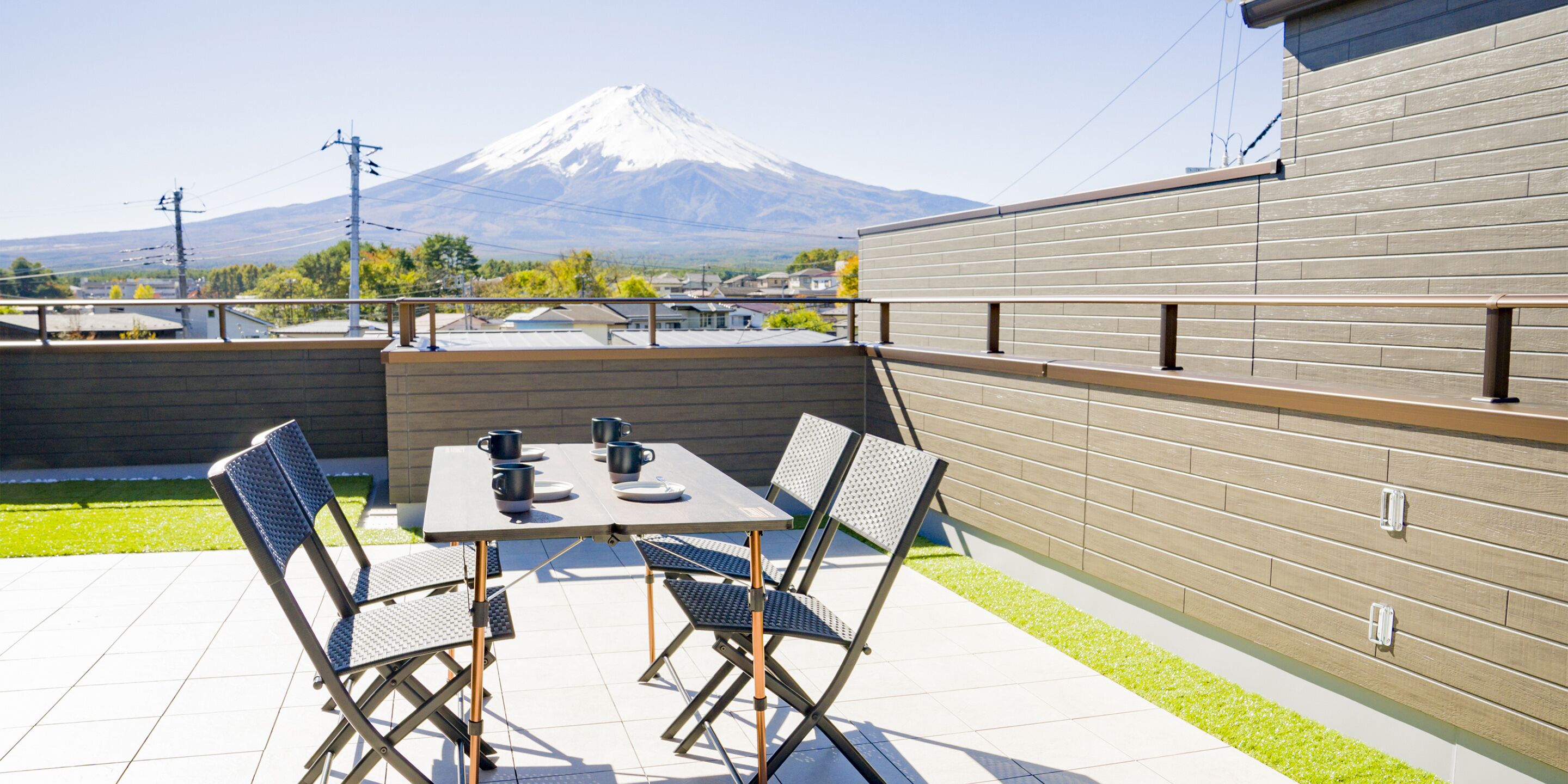 A patio with a table and chairs, a view of a mountain, and a brick wall.