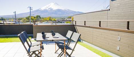 A patio with a table and chairs, a view of a mountain, and a brick wall.