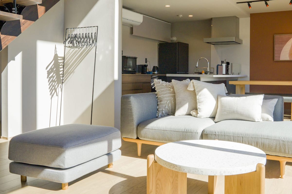 Ein modernes Wohnzimmer mit einer Eckcouch, einem runden Couchtisch und einer Treppe mit außergewöhnlichem Design.