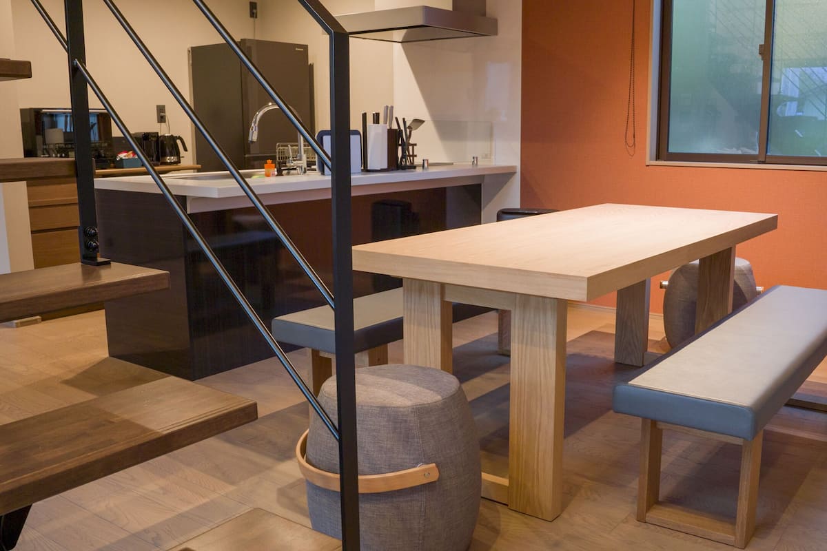 Eine moderne Küche mit Holztisch, Bank und Treppe.