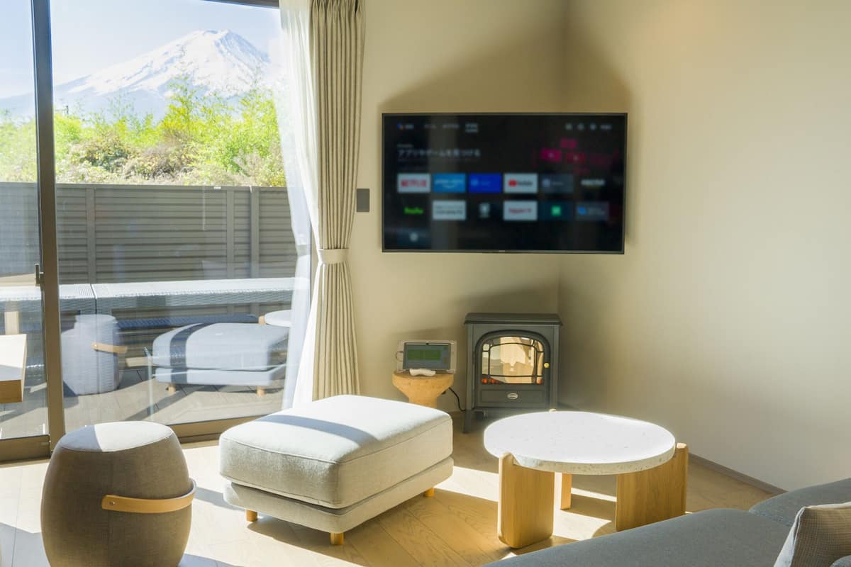 Ein modernes Wohnzimmer mit Flachbildfernseher an der Wand, einem Kamin und einer Couch mit Kissen.