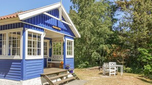 A blue and white building with a porch, a wooden bench, and a table outside. - Beautiful home in Nexø with sauna (Nexø)