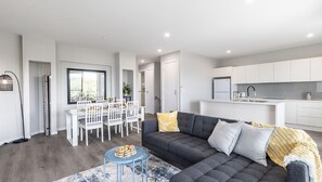 Un appartement moderne comprenant un coin repas, un salon avec un canapé gris et une cuisine.