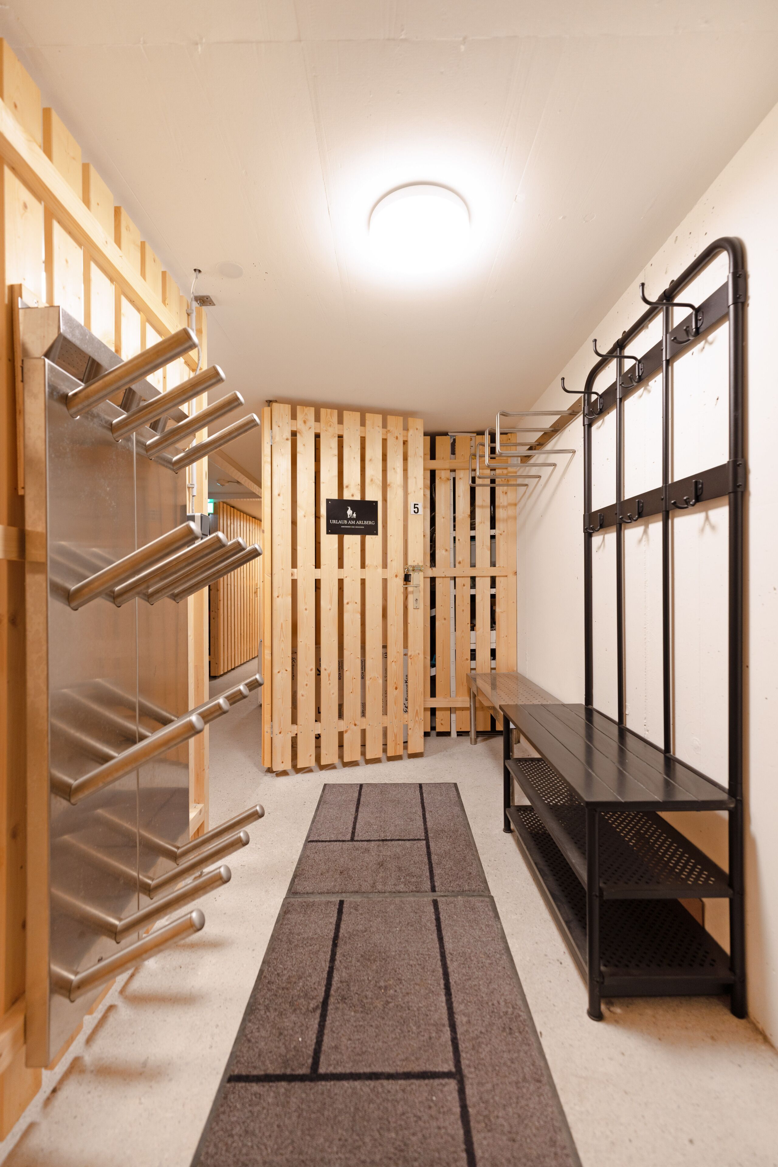 A hallway with wooden lockers, metal shelves, and a bench.