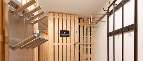 A hallway with wooden lockers, metal shelves, and a bench.