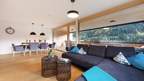 Un salon moderne avec un canapé foncé, des tables basses rondes et un coin repas comprenant des chaises et une table.