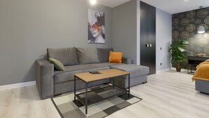 A modern living room with a grey sofa, a wooden coffee table, and a patterned rug.