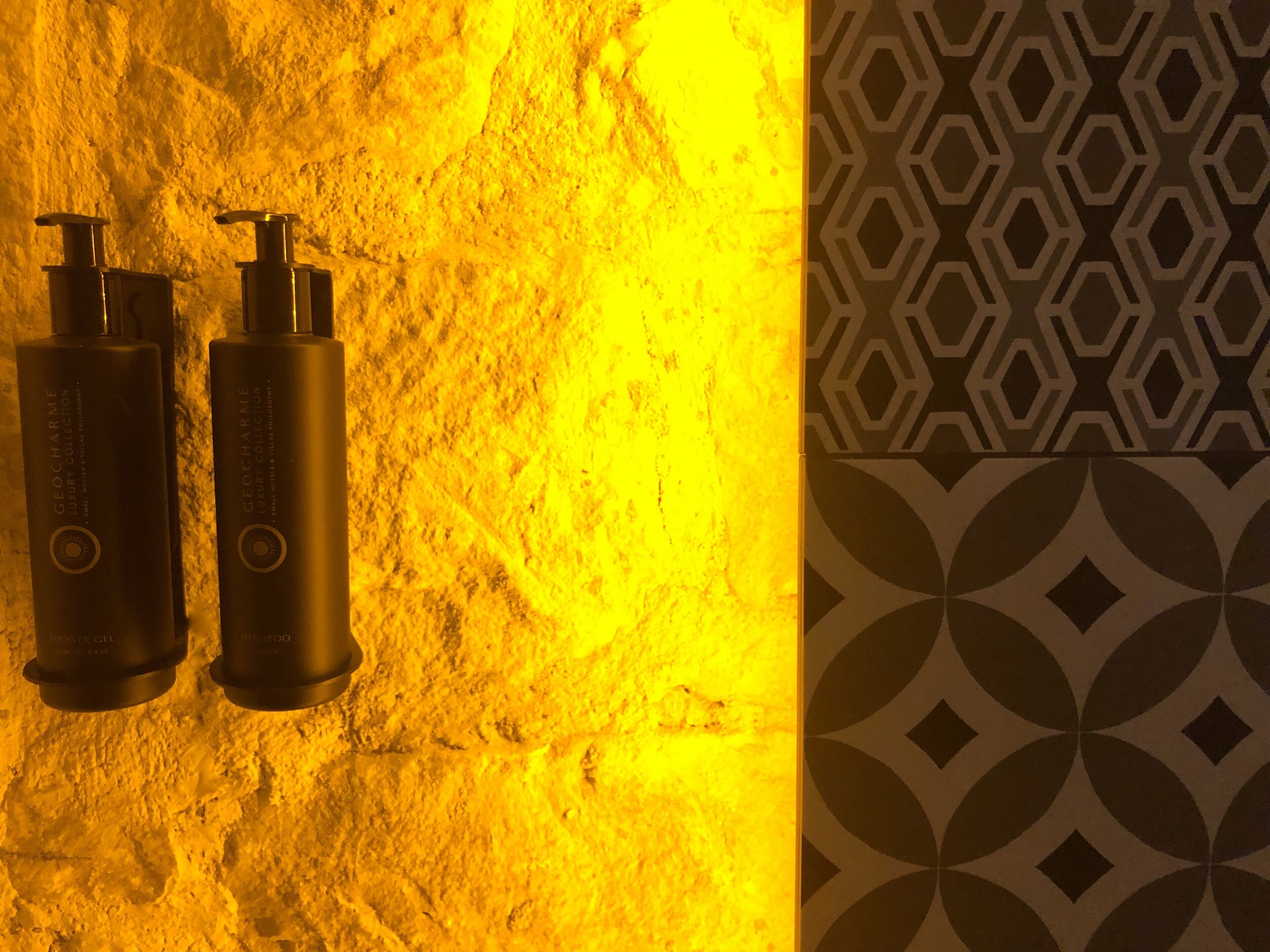 Two bottles of Geocharm luxury collection on a textured wall.