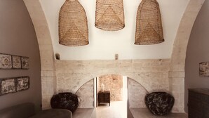 Une pièce spacieuse avec une cheminée en pierre, un canapé et trois luminaires en fibres tressées.
