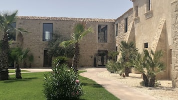 A courtyard with stone buildings, palm trees, and a pathway.