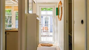 A hallway leading to a door with a view of outdoor furniture and a deck.