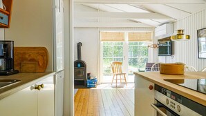 A kitchen with a wood stove, a coffee maker, and a TV mounted on the wall.