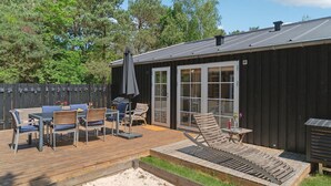 A deck with outdoor furniture, a grill, and a covered seating area.