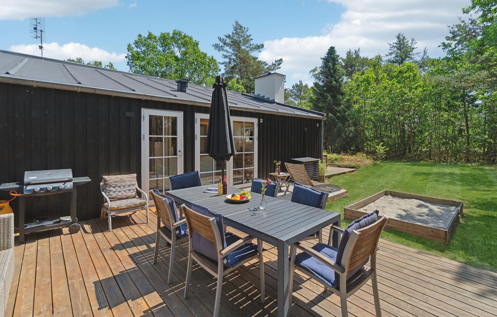 A deck with a table and chairs, a grill, and a barbecue area.