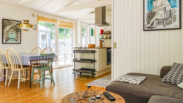 A cozy living room with a wooden floor, a gray sofa, and a dining area with a table and chairs.