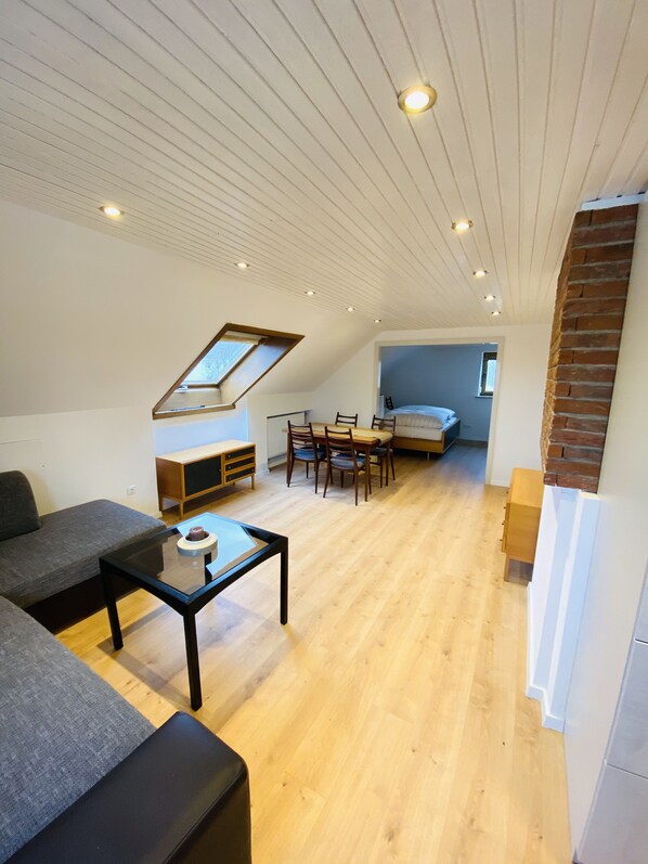 Un loft moderno con comedor, sofá y pequeña cocina.