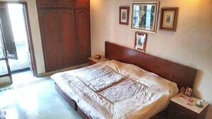 A bedroom with a large bed, wooden wardrobe, and a nightstand with a lamp. - 2 Bed Apartment Sleeps 4 With Parking New Delhi (New Delhi)