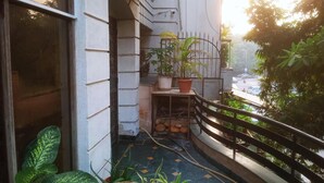 A balcony with potted plants, a metal railing, and a view of the street below. - 2 Bed Apartment Sleeps 4 With Parking New Delhi (New Delhi)