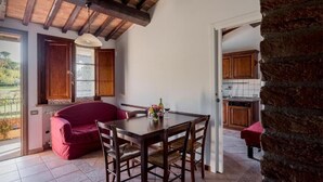 Un comedor con una mesa y sillas de madera, un sofá rojo y vistas a la cocina.