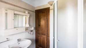 Un baño con un lavabo blanco, un espejo y una puerta de madera.