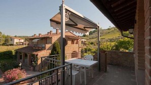 Un patio con una mesa y sillas, con vistas a una colina con edificios.