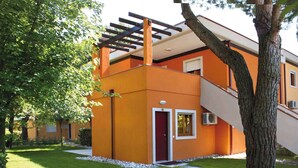 Un edificio moderno con una porta rossa, una scala e una pergola.