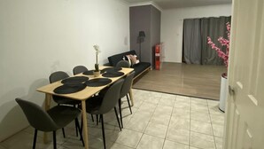 A dining area with a table and chairs, a potted plant, and a sofa. - Spacious 3 bedroom townhouse with AC and lock up garage (Liverpool)