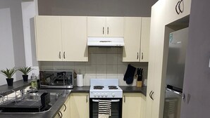 A compact kitchen with a stove, oven, and refrigerator. There are cabinets, a sink, and a countertop. - Spacious 3 bedroom townhouse with AC and lock up garage (Liverpool)
