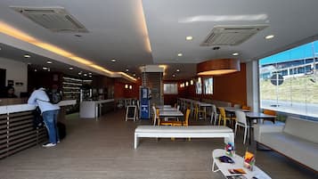 Een modern restaurantinterieur met een balie, zitgedeelte en grote ramen.