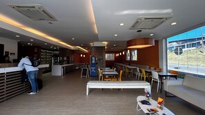 Un intérieur de restaurant moderne, avec un comptoir, un espace salon et de grandes fenêtres.