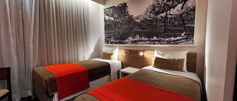 A hotel room with two beds, a large window with curtains, and a wall-mounted painting.