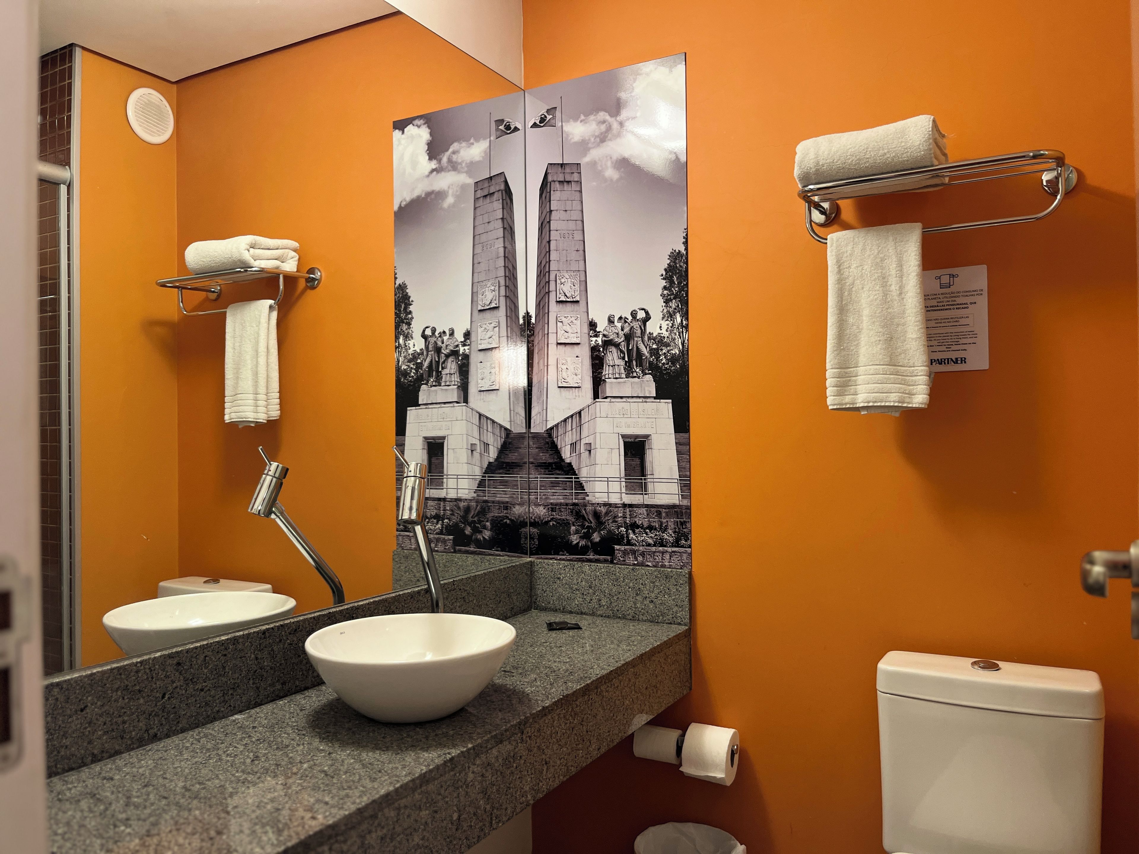 A bathroom with a white sink, a mirror, a toilet, and a towel rack.