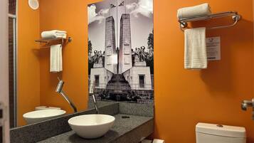A bathroom with a white sink, a mirror, a toilet, and a towel rack.