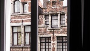 Uitzicht vanuit een raam op een meerlaags gebouw met bakstenen gevels en veel ramen.