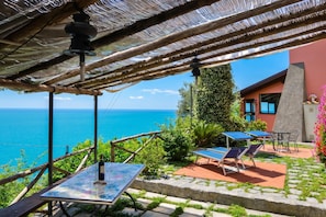 A terrace with a table, chairs, and a view of the sea.
