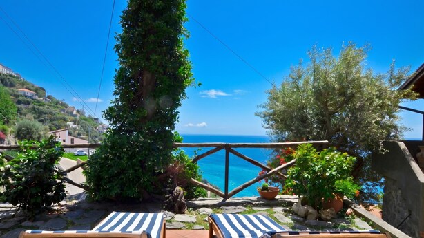 Una terraza con dos sillones de descanso, vista al mar y un sendero de piedra.