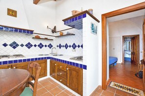 A kitchen with wooden cabinets, a dining table, and blue and white tiles.