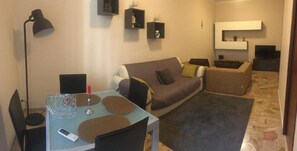 A compact living space with a sofa, a small table, a lamp, and a TV.
