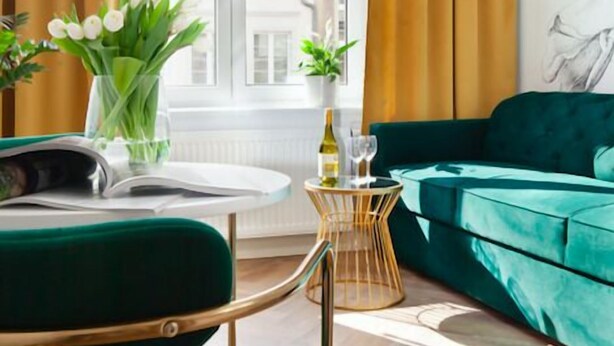 A modern living room with a green sofa, a wooden coffee table, and a vase with flowers. - Elite Apartments Ogarna Prestige (Gdansk)